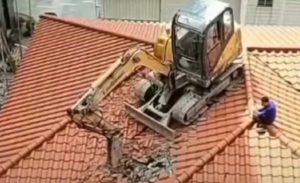 Kocak Sekarang Giliran Ekskavator yang Nyangkut di Genteng Rumah Warga